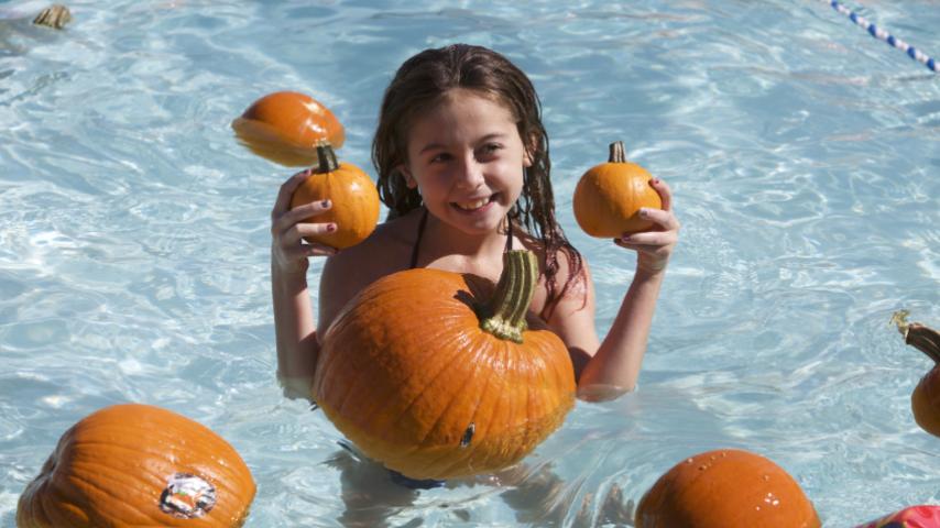 girl holding pumpkins in the pool