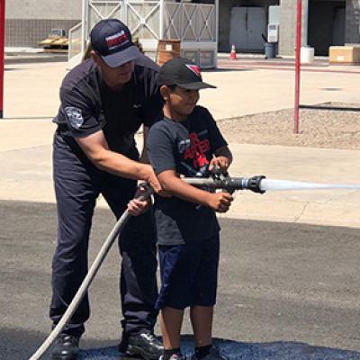 Chandler firefighter showing a child how to operate a fire hose