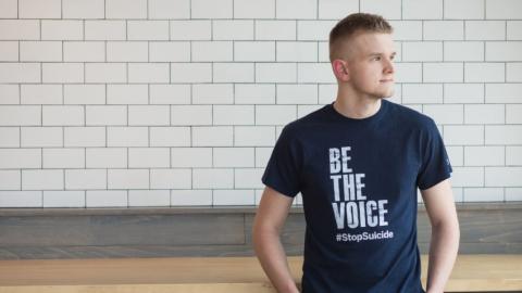Sam Eaton, founder of Recklessly Alive, wearing a black t-shirt with text: Be the Voice #StopSuicide