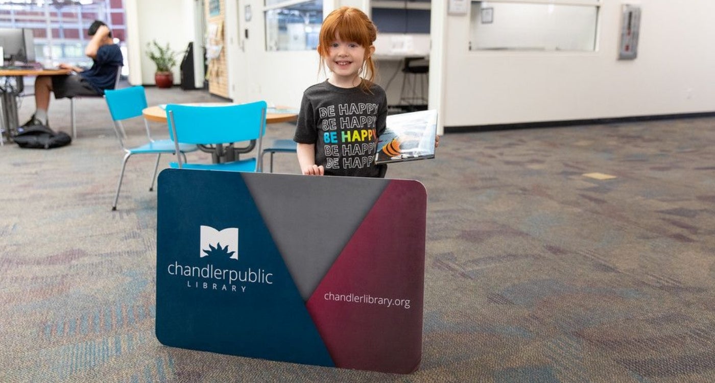 Young girl holding an oversized library card