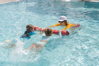 swim instructor teaching two children