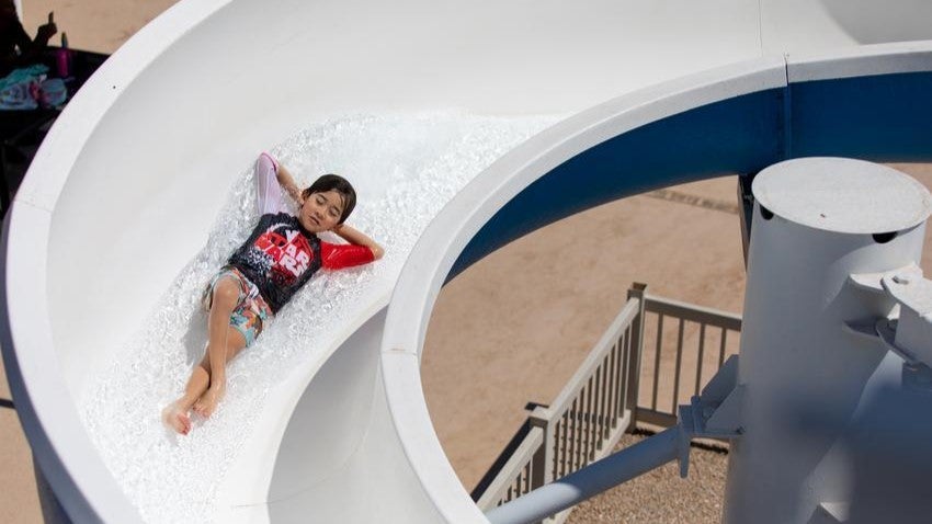 Young swimmer going down water slide