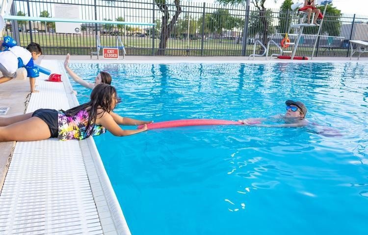 girl reaching for lifeguard with noodle