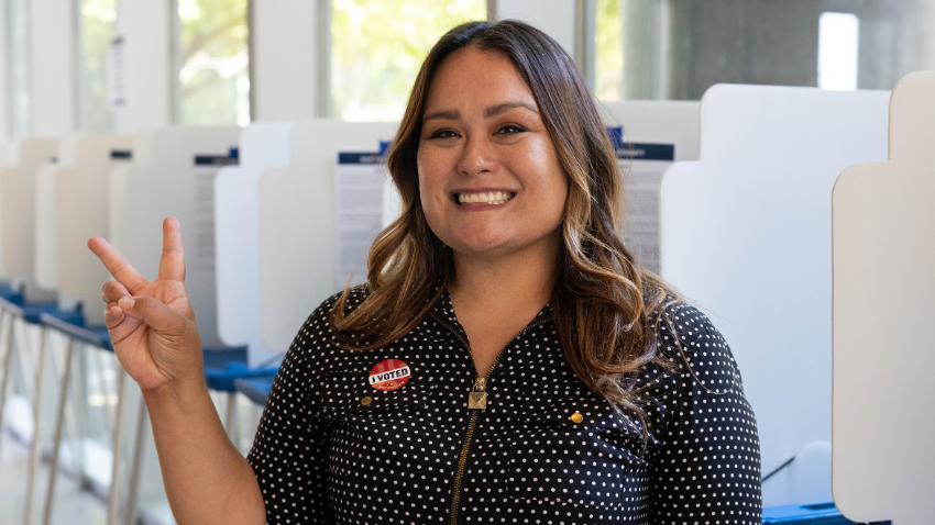 Female voter making a peace sign wearing an I Voted sticker