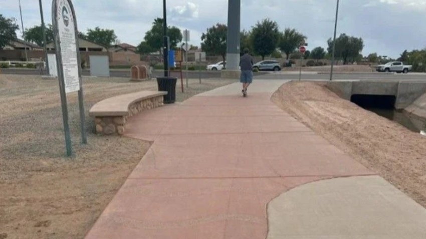 man walking along Paseo Trail nearing a main road