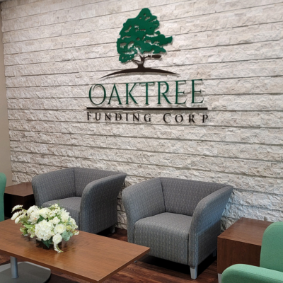 Lobby of Oaktree Funding Corp, logo on the wall with chairs and table