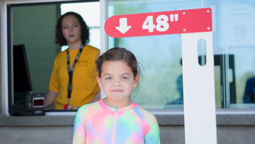 Young girl measuring height under 48 inches sign
