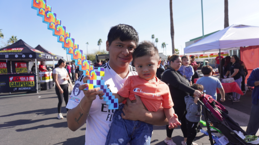 Father holding a child in his arms while holding a toy