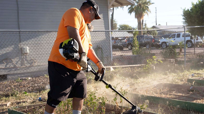 Man using trimmer to cut weeds
