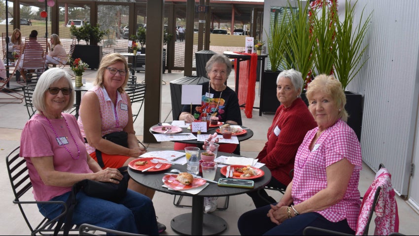 five women sitting around a circular table eating and talking