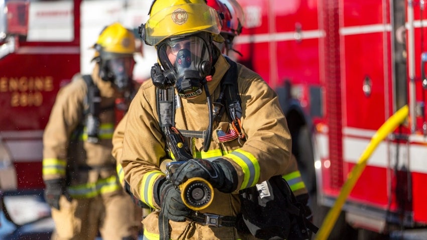 Firefighter in full gear demonstrating the fire hose.