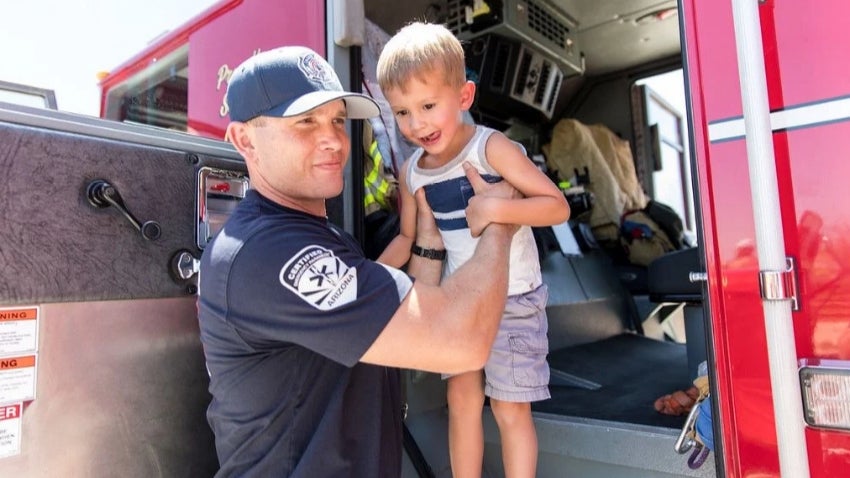 Firefighter lifting a child out of the fire truck