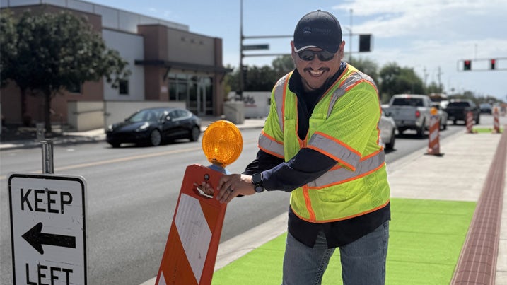 City worker is moving traffic cones on the side of a street 