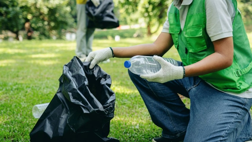 Man bagging trash in a yard