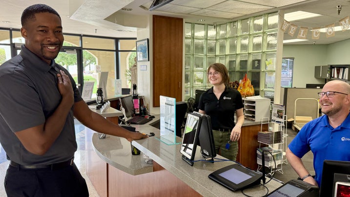 James, a Chandler employee is standing at the desk of a chandler community center talking to his co-workers