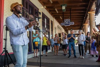 Man playing alto saxophone in front of a crowd of people in Downtown Chandler