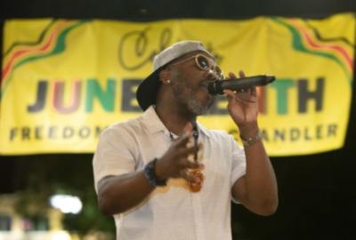 Vaughn Willis performing in front of Juneteenth banner