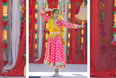 Woman in a traditional Indian dress dancing on a stage surrounded by red and gold drapery and decor