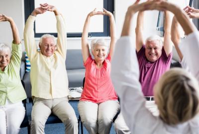 Group of senior residents stretching their hands while seated