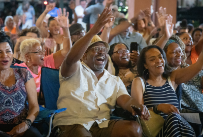 Group of people sitting and raising arms in celebration