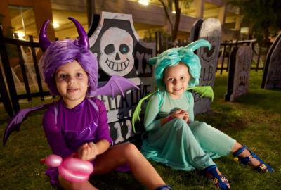 Child in purple Halloween costume sitting next to a child in a light blue Halloween costume
