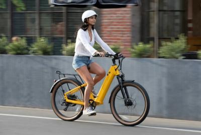 Woman wearing a white helmet riding yellow E-bike along concrete path.