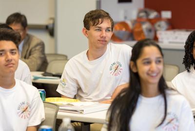 Four teenagers sitting at a table in white shirts