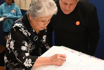 Woman pressing stamp into book while man looks over her shoulder
