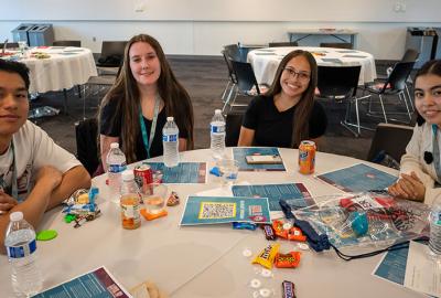 Four young adults sit around a table smiling at the camera