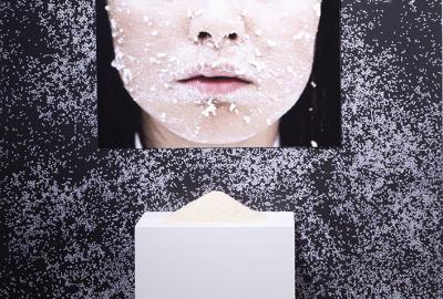 Picture of a woman's nose and mouth in front of a pedestal with clay rice