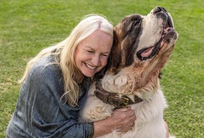 Woman with blonde hair hugging a Saint Bernard dog