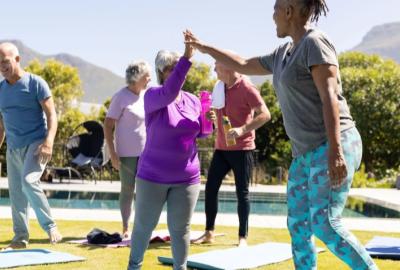 Seniors high-fiving standing on yoga mats 