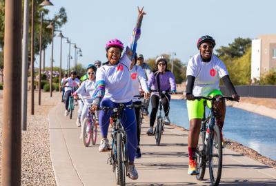 Woman riding a bike throwing up a peace sign with her left arm overhead