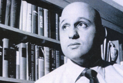 Eddie Basha from the chest up in front of a book shelf