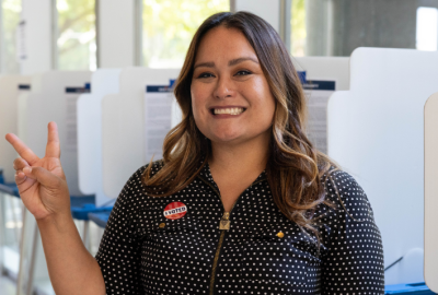 Chandler female voter holding up a peace sign wearing a I Voted sticker on her shirt