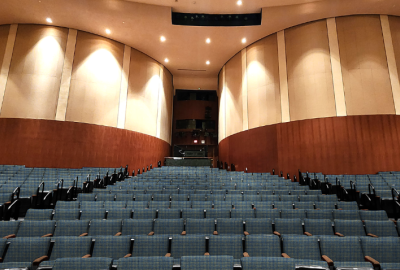 Theater with blue upholstered seats in front of large, round columns