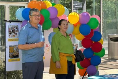 Seniors attending Golden Neighbors celebration; standing in front of a colorful balloon arch