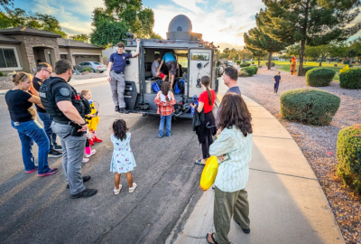 Chandler Police with neighbors during a 2025 G.A.I.N. event; police vehicle in the background with officer and kids inside