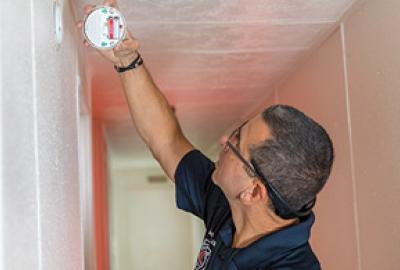 photo showing someone installing a smoke alarm in a house