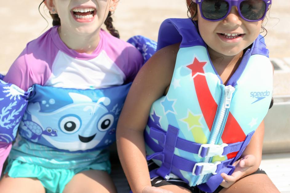 kids poolside wearing lifejackets
