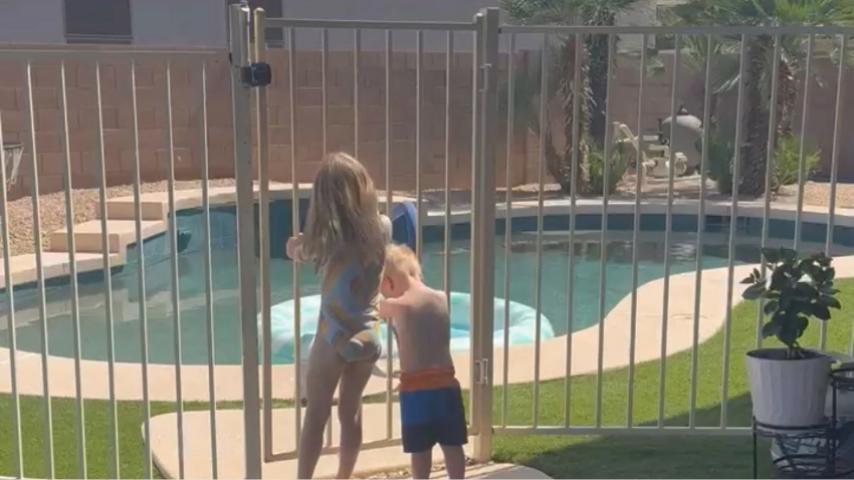 two kids in front of a locked pool fence