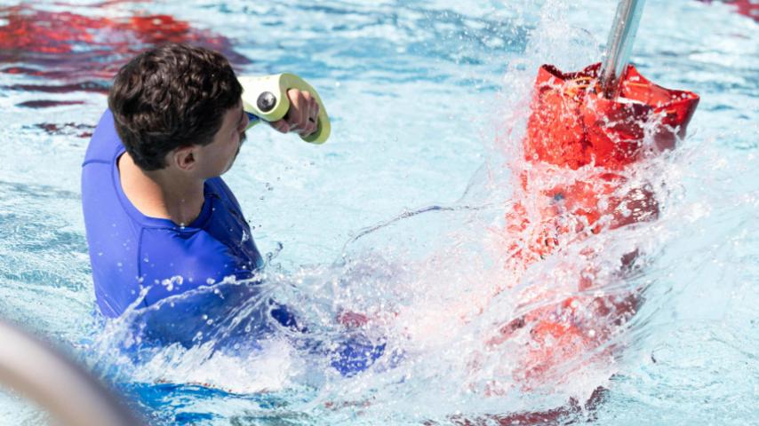 a man in a swimming pool punching a fitness bag for fitness. 