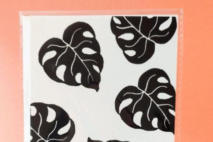 paper with prints of black monstera plant leaves on it