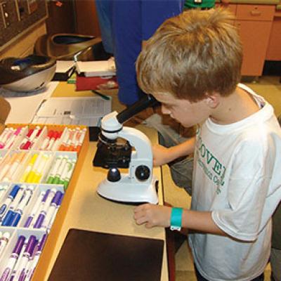 Science camp participant looking under a microscope