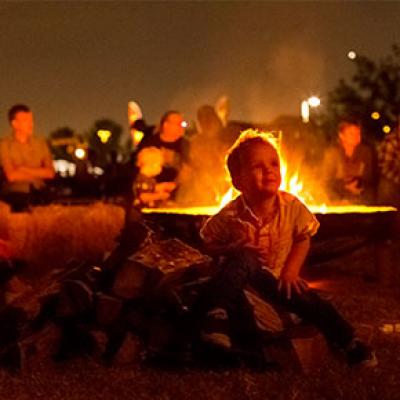 A young child sitting by the campfireatthe2017ChuckWagonCookoff