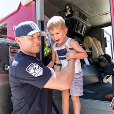 Chandler firefighter assisting a young child out of a fire truck