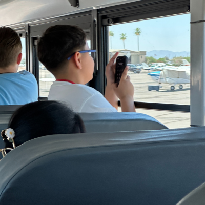 child taking a photo out of the bus window of small aircraft at Chandler Airport