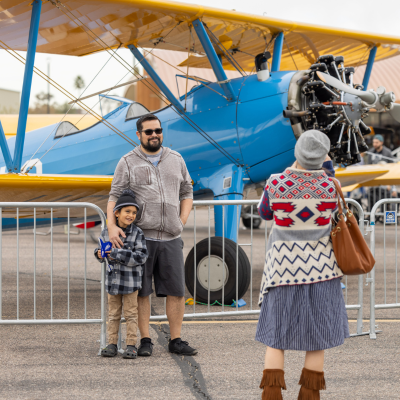 Father and child smile as their photo is taken in front of a plane