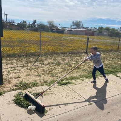 young boy sweeping sidewalk