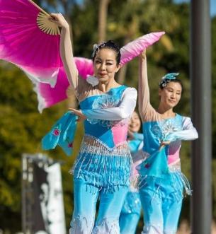 Asian dancers performing online waving large pink fans